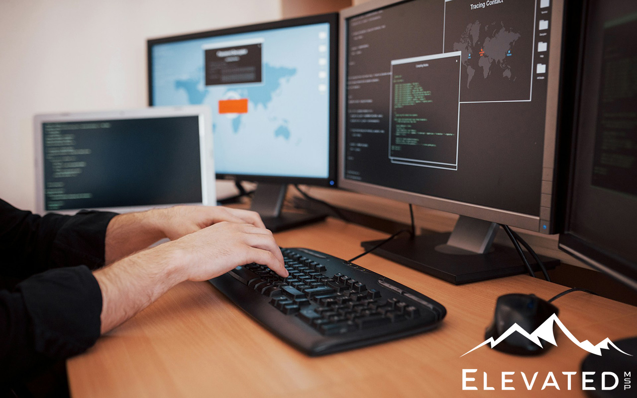 Man typing on keyboard while his monitor shows lines of code.